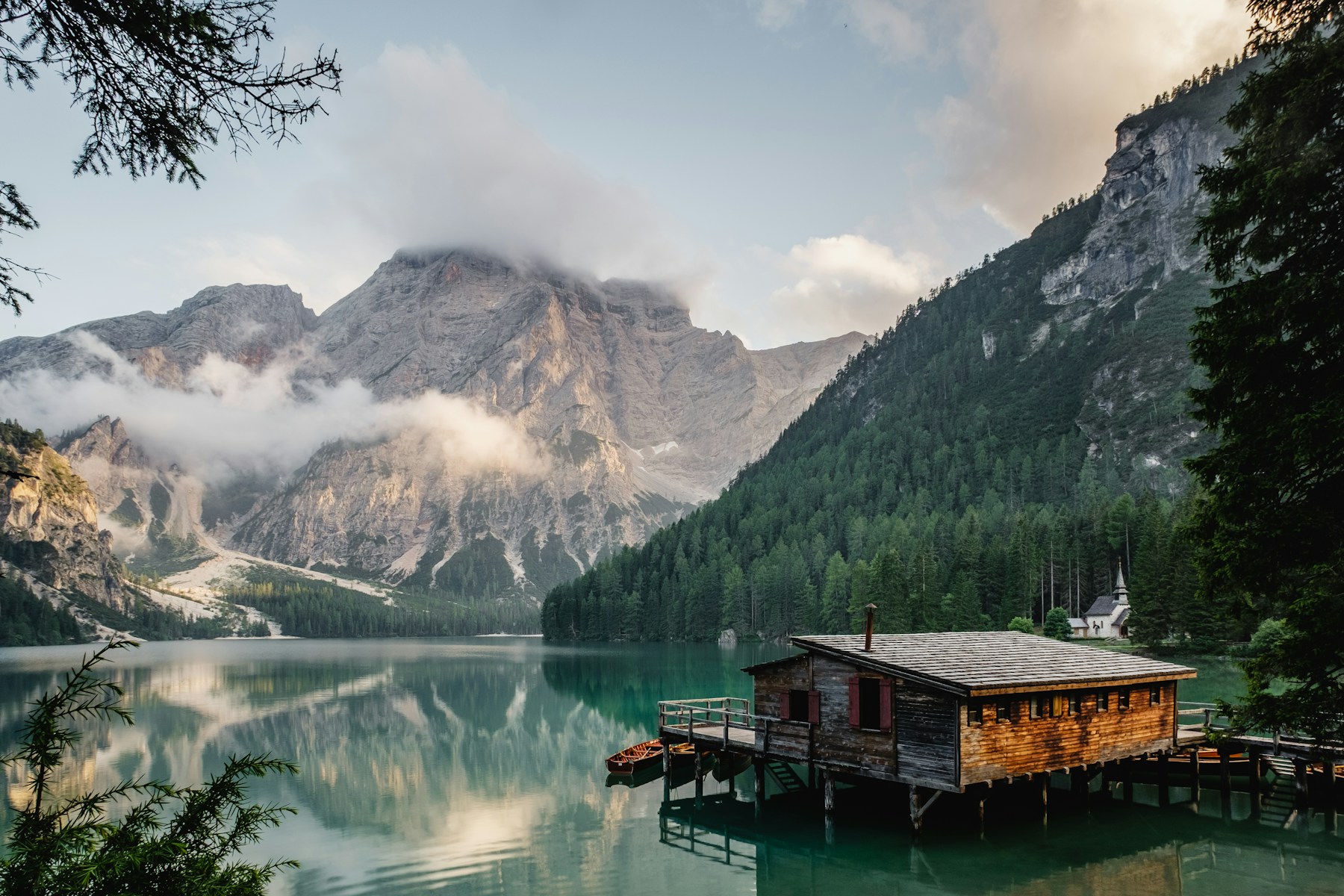 A mountain, forest and cabin reflected in a still alpine lake